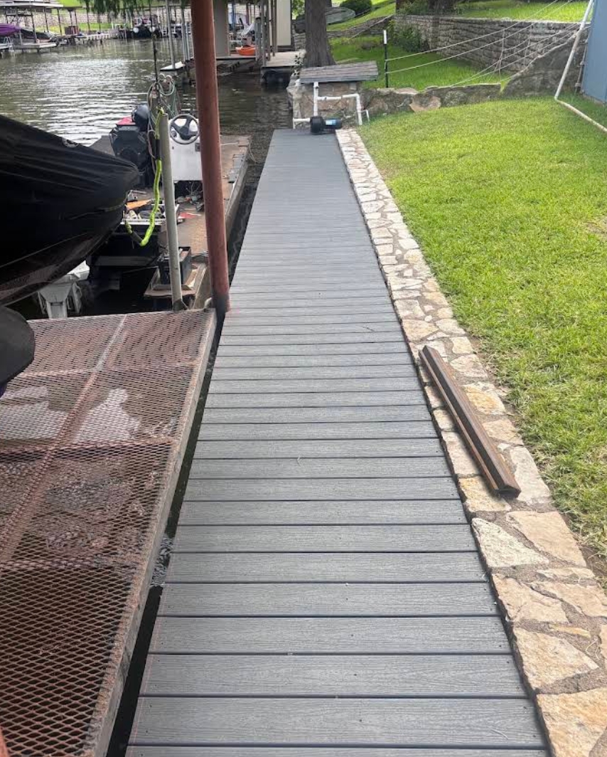 New composite walkway laid along a stone retaining wall beside an old metal dock being replaced