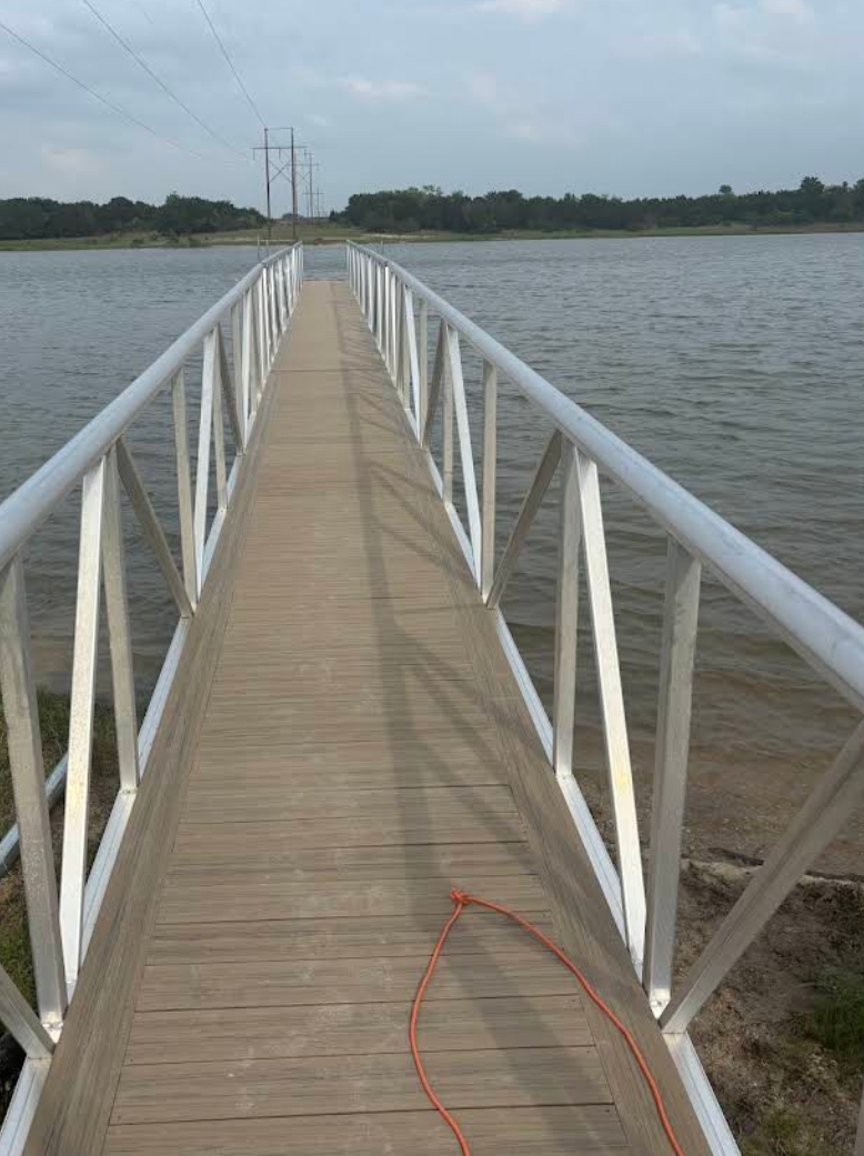 Long aluminum gangway with picket railing running out over the water to a dock