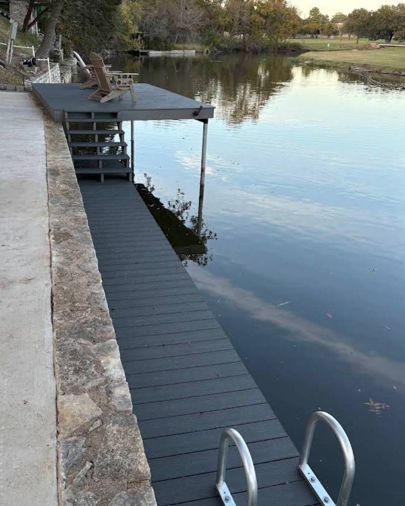 Lakeside composite walkway leading to a covered deck with Adirondack chairs in evening light — built by Waters Edge Docks & More